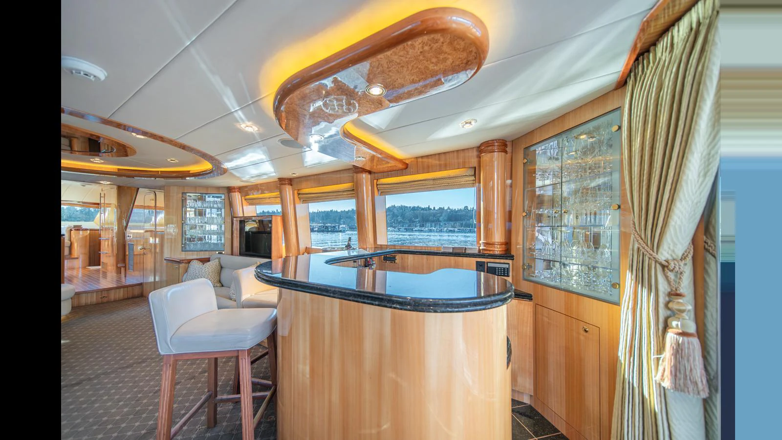 The yacht's salon features a stylish bar area with panoramic windows offering stunning views. aboard WISHES GRANTED Yacht for Sale