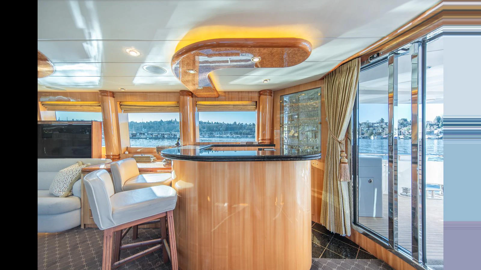 The saloon features a stylish bar area with panoramic windows offering stunning water views. aboard WISHES GRANTED Yacht for Sale