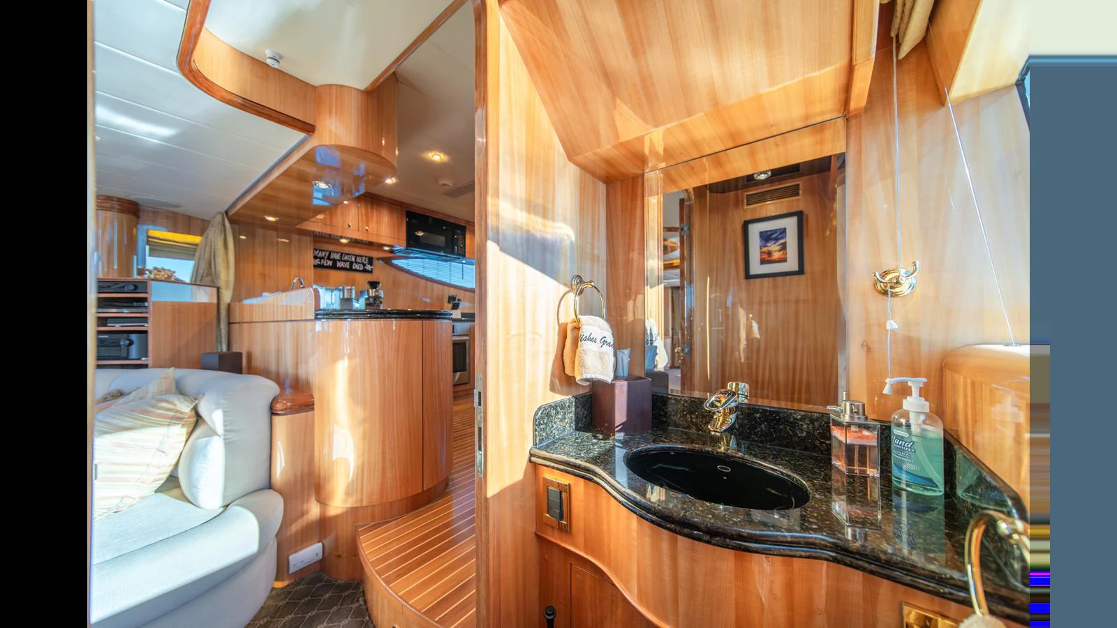 The yacht's bathroom features elegant wood paneling and a sleek black countertop. aboard WISHES GRANTED Yacht for Sale