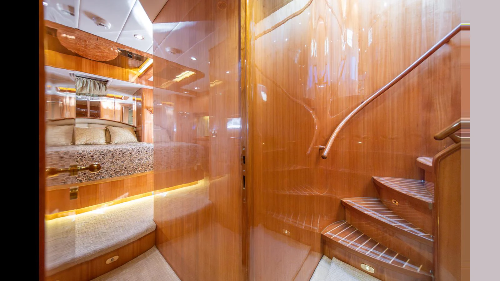 The image showcases a luxurious wooden staircase leading to a cozy stateroom. aboard WISHES GRANTED Yacht for Sale