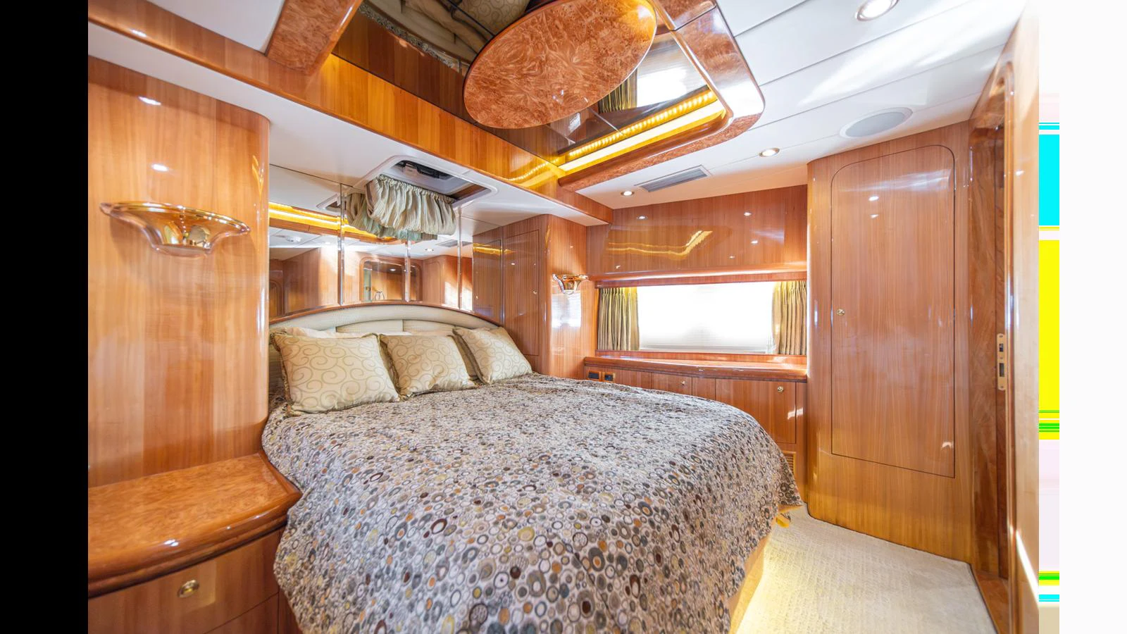 The master stateroom features a luxurious bed with elegant wood finishes and ample natural light. aboard WISHES GRANTED Yacht for Sale
