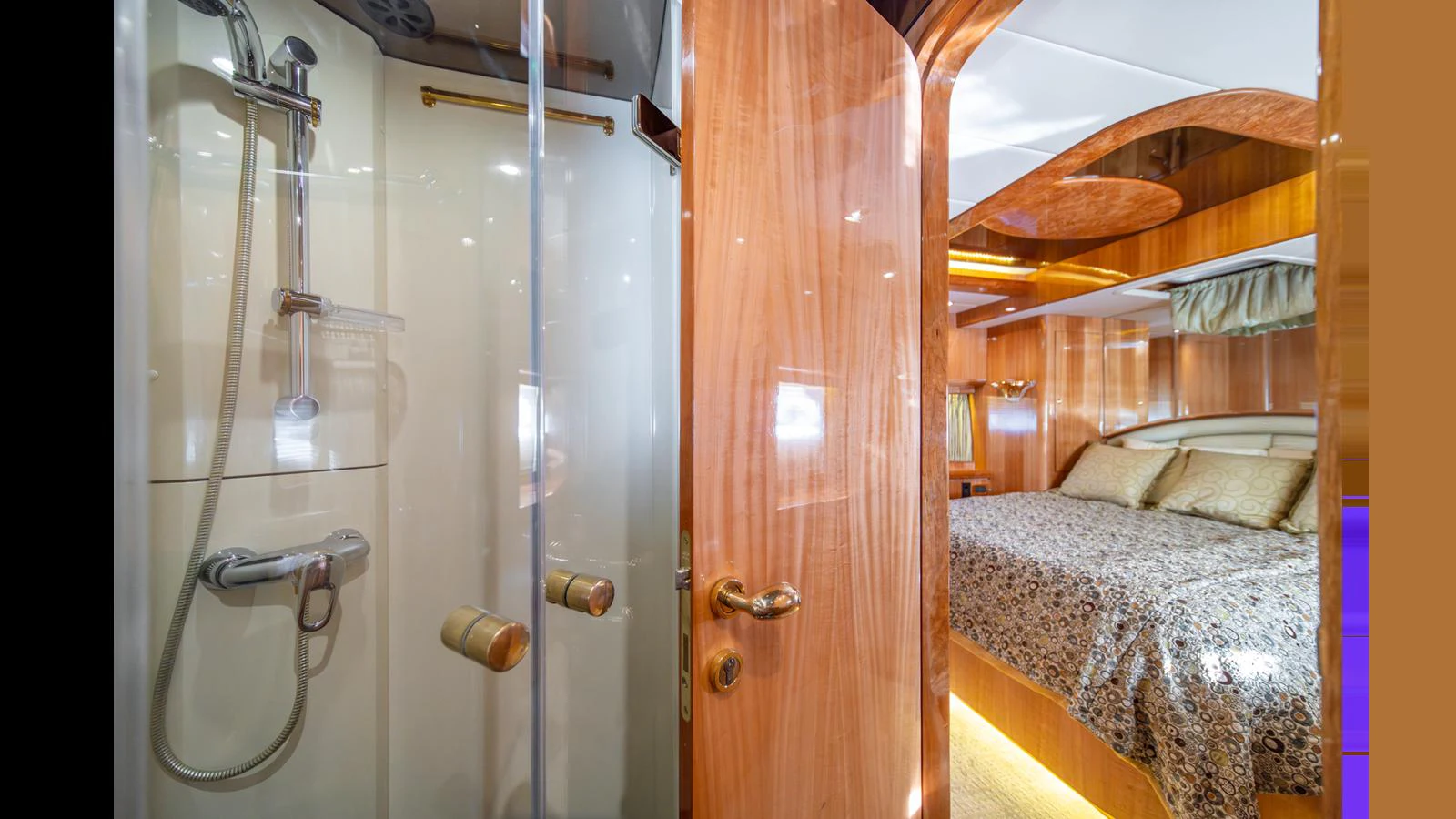 The image showcases a luxurious stateroom with an en-suite bathroom, featuring elegant wood finishes and a comfortable bed. aboard WISHES GRANTED Yacht for Sale