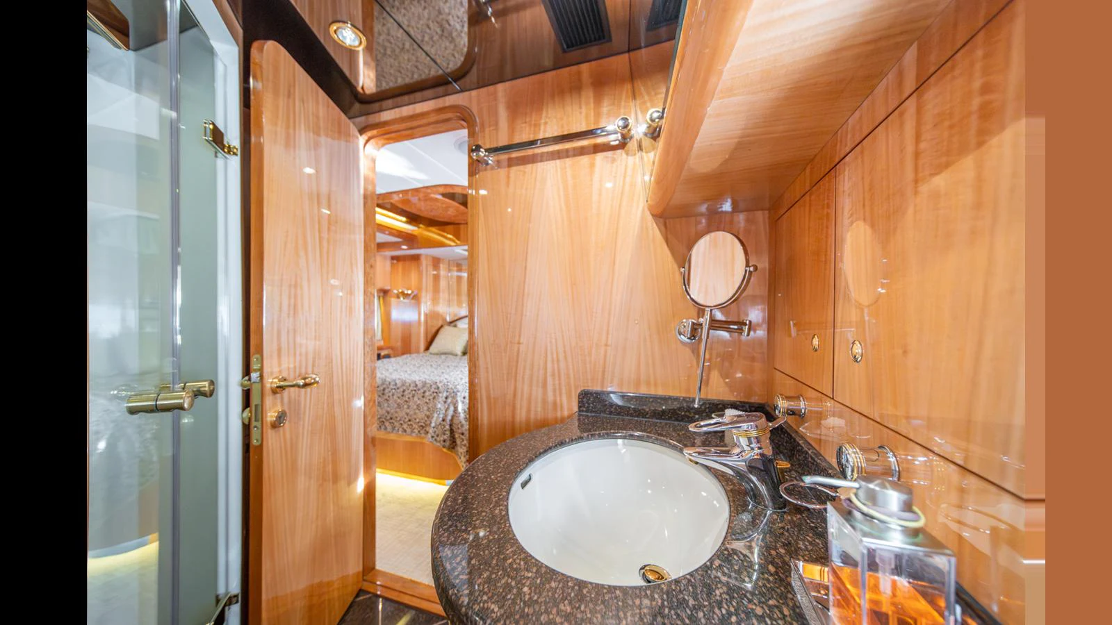 The yacht's bathroom features luxurious wood paneling and a sleek granite countertop. aboard WISHES GRANTED Yacht for Sale