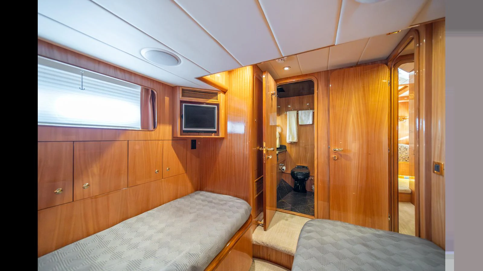 The guest cabin features twin beds, warm wood paneling, and an en-suite bathroom. aboard WISHES GRANTED Yacht for Sale