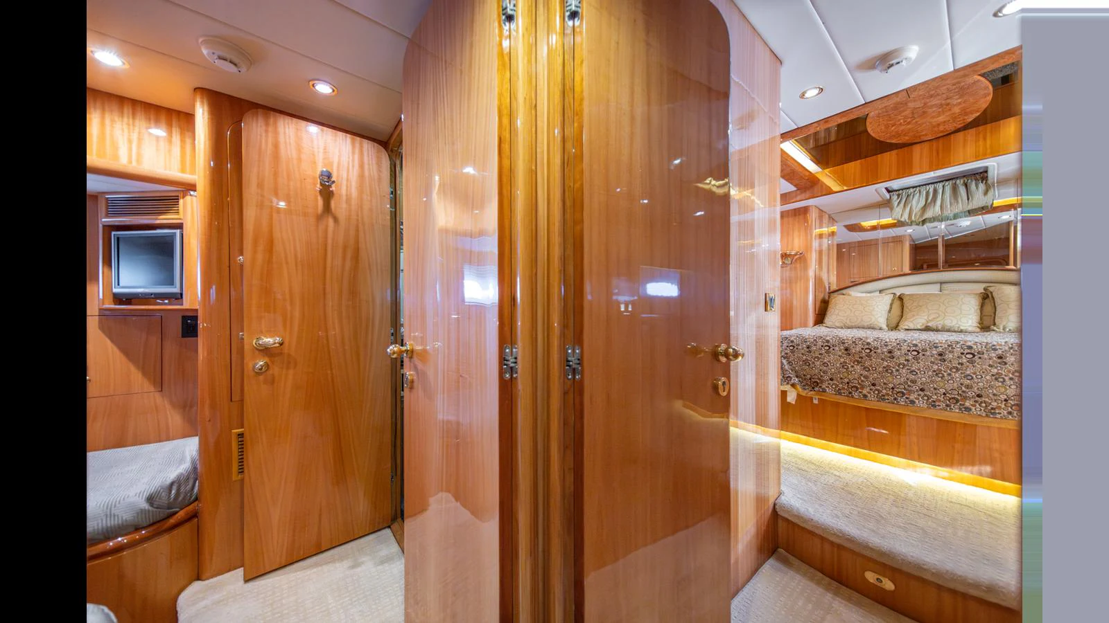 The image showcases a luxurious stateroom with polished wooden finishes and a cozy bed. aboard WISHES GRANTED Yacht for Sale
