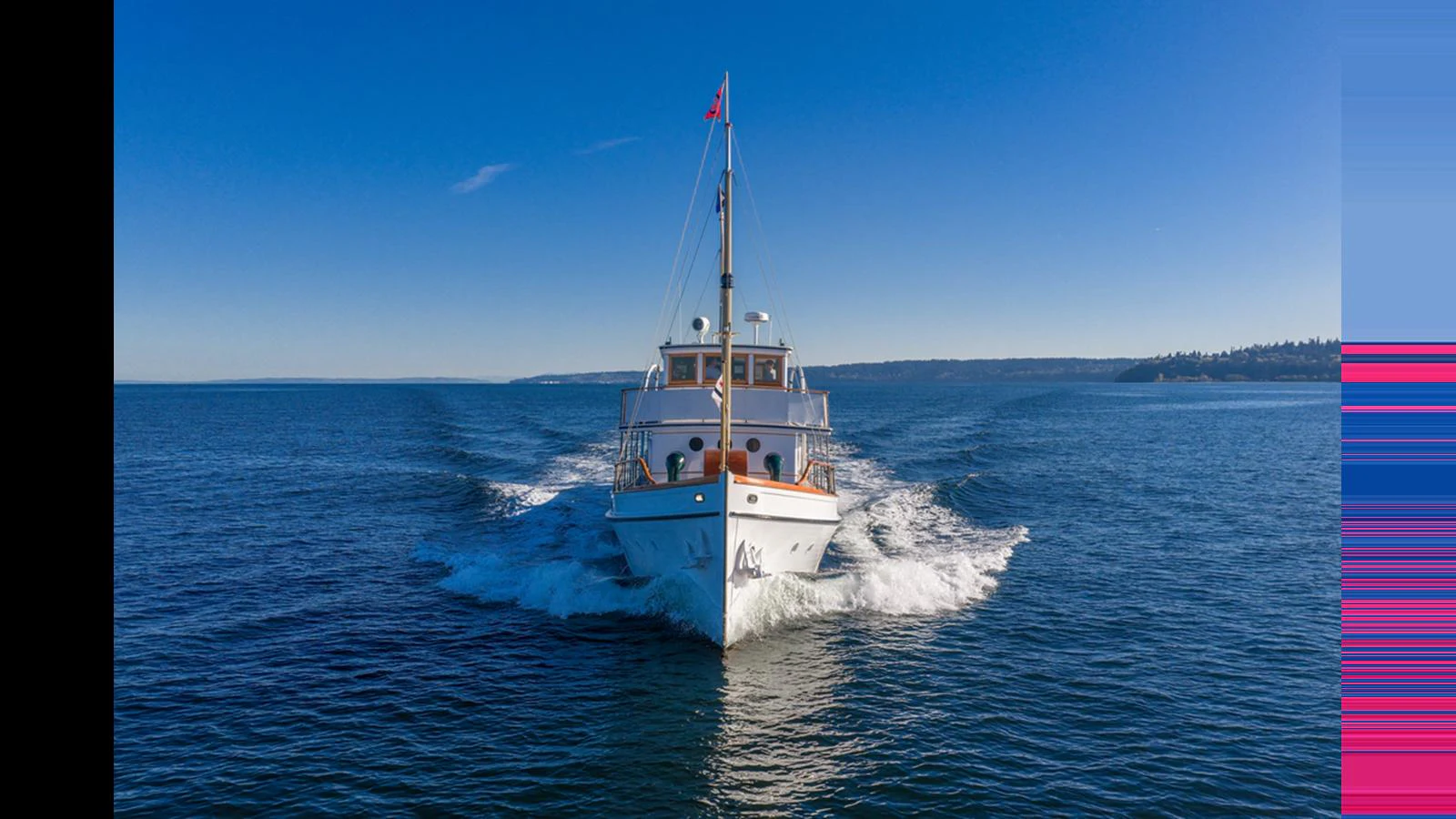 A classic yacht cruises through calm waters under a clear blue sky. aboard BLUE PETER Yacht for Sale
