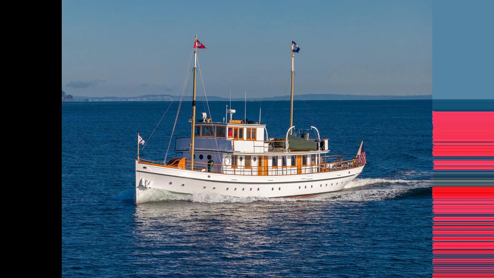 A classic yacht cruises gracefully on calm blue waters under a clear sky. aboard BLUE PETER Yacht for Sale