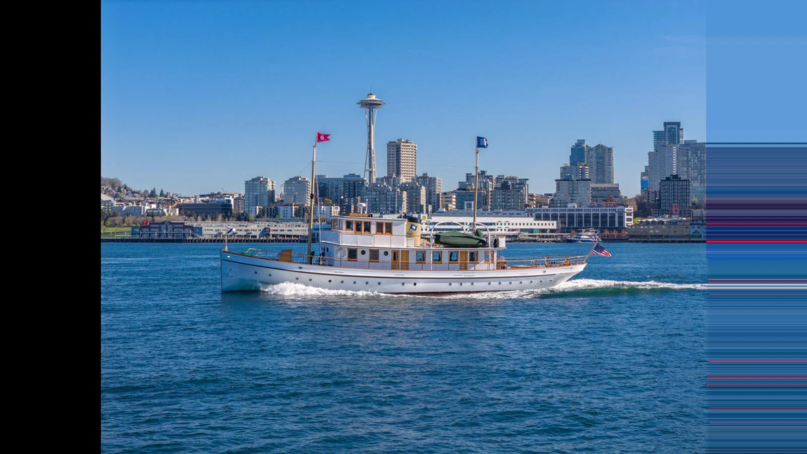 A classic yacht cruises gracefully against a city skyline backdrop. aboard BLUE PETER Yacht for Sale