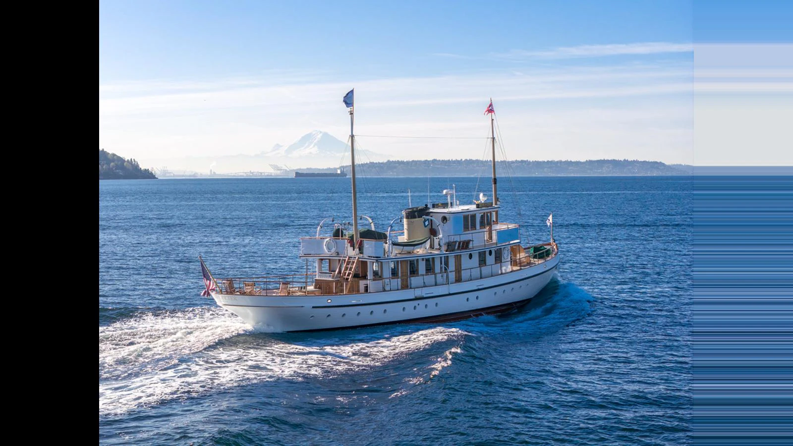 A classic yacht cruises gracefully on a calm sea with a scenic backdrop. aboard BLUE PETER Yacht for Sale