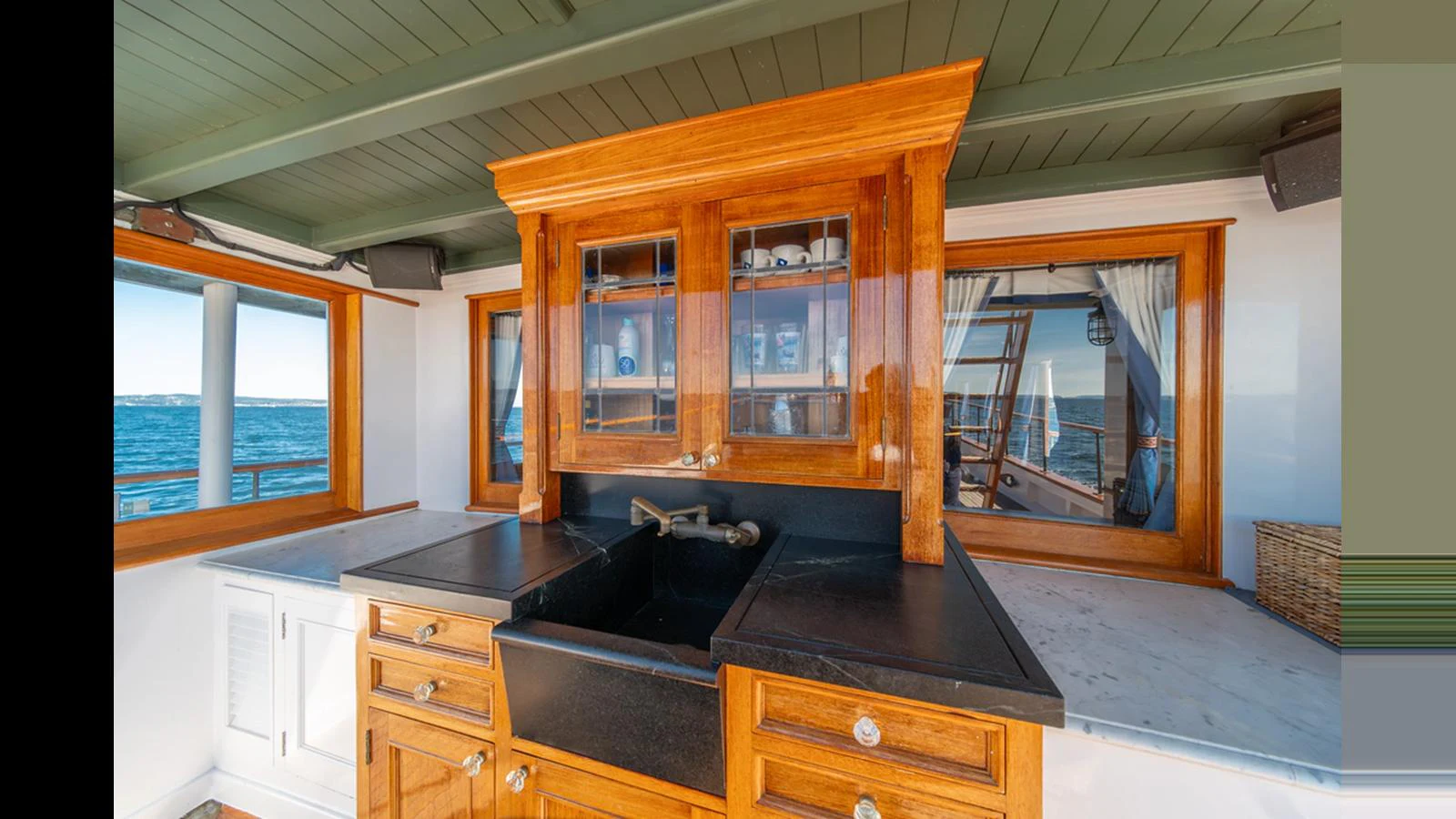 The yacht's galley features elegant wooden cabinetry and a sleek black countertop with a built-in sink. aboard BLUE PETER Yacht for Sale