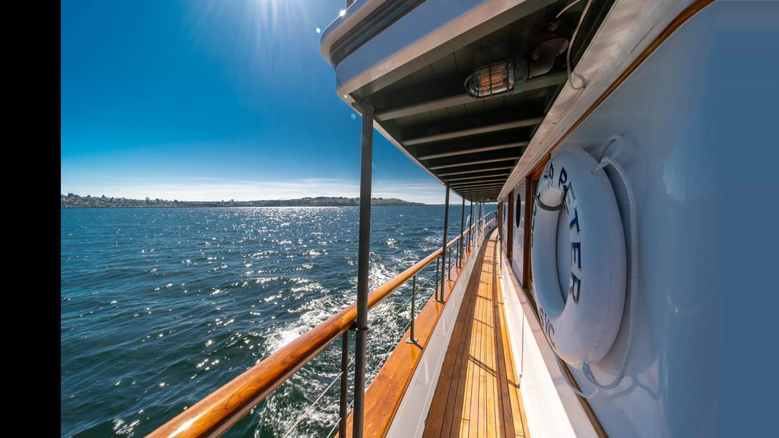 The yacht's side deck offers a stunning view of the sparkling water under a clear blue sky. aboard BLUE PETER Yacht for Sale