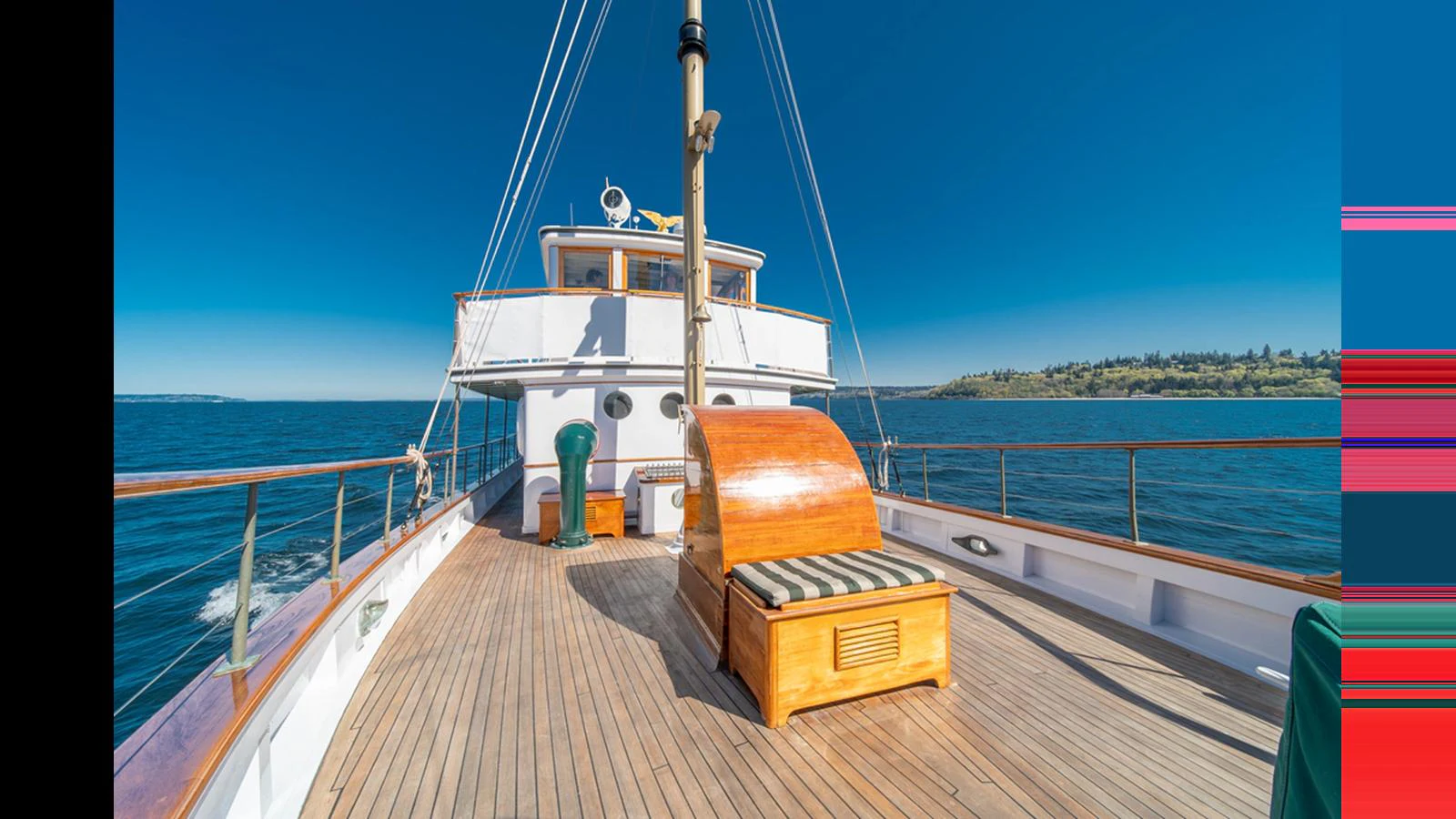 The foredeck of the yacht features a wooden deck with a cushioned seating area, offering a serene view of the open water. aboard BLUE PETER Yacht for Sale