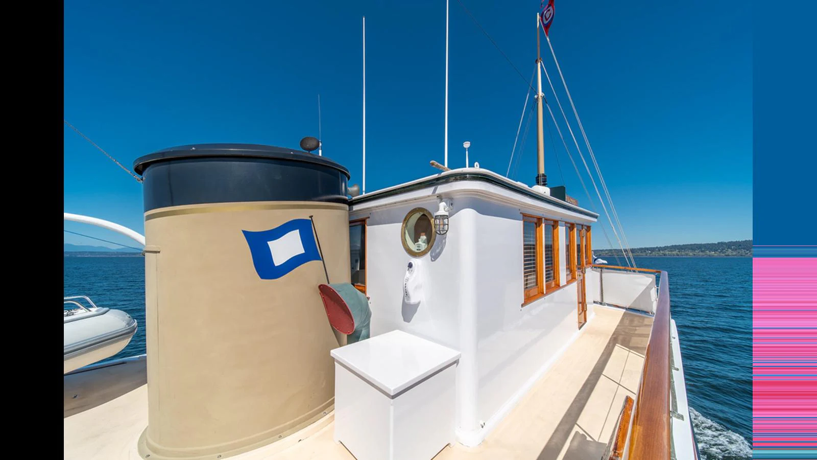 The yacht's deck features classic design elements with a prominent funnel and a bright, clear sky above. aboard BLUE PETER Yacht for Sale