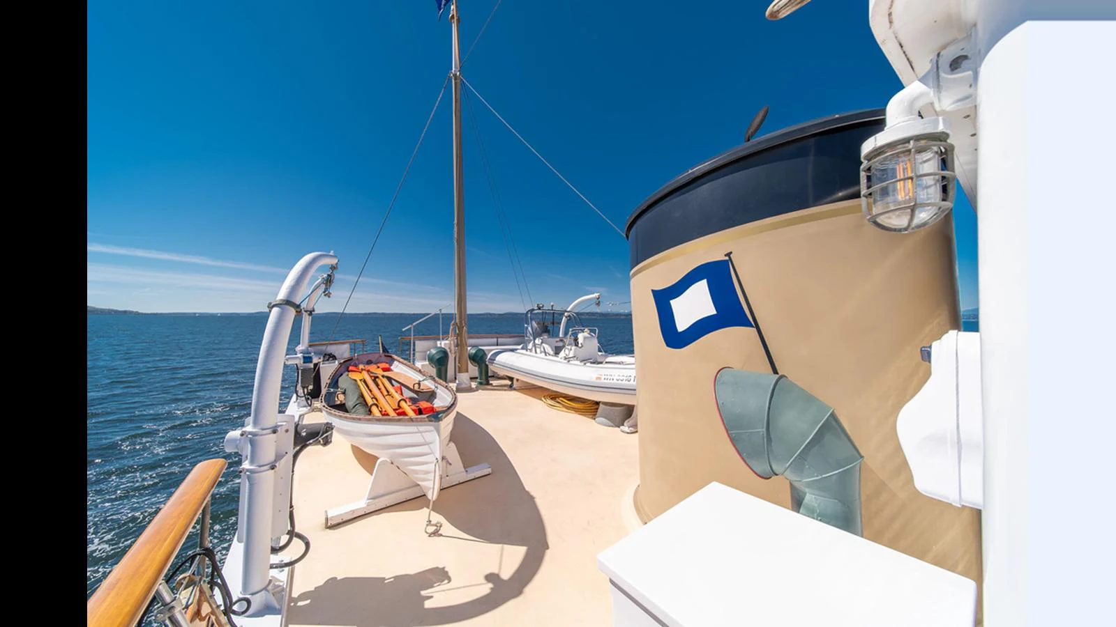 The deck of the yacht features a lifeboat and a clear view of the surrounding waters. aboard BLUE PETER Yacht for Sale