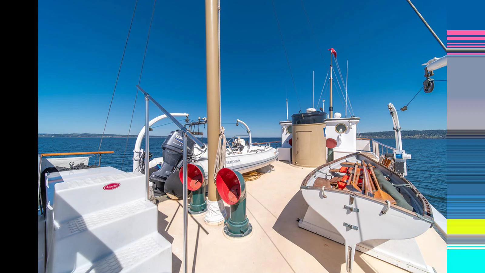The yacht's deck is equipped with lifeboats and other essential equipment under a clear blue sky. aboard BLUE PETER Yacht for Sale