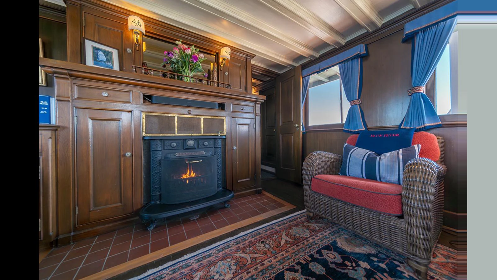 The salon features a cozy fireplace, elegant wood paneling, and comfortable seating. aboard BLUE PETER Yacht for Sale