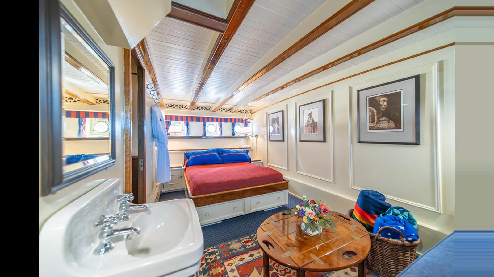 A cozy stateroom featuring a comfortable bed, wooden beams, and a small sink area. aboard BLUE PETER Yacht for Sale