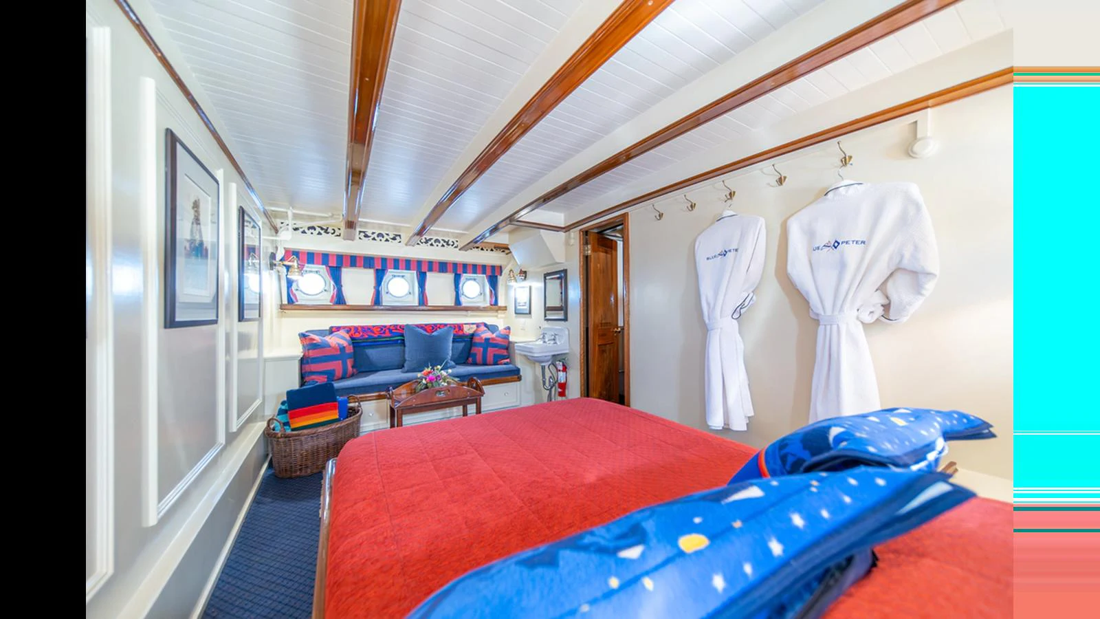 The stateroom features a cozy bed with vibrant linens and a seating area, creating a comfortable and inviting atmosphere. aboard BLUE PETER Yacht for Sale