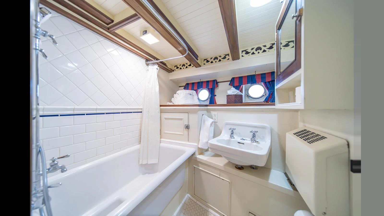 The bathroom features a classic design with a bathtub, white tiles, and nautical-themed accents. aboard BLUE PETER Yacht for Sale