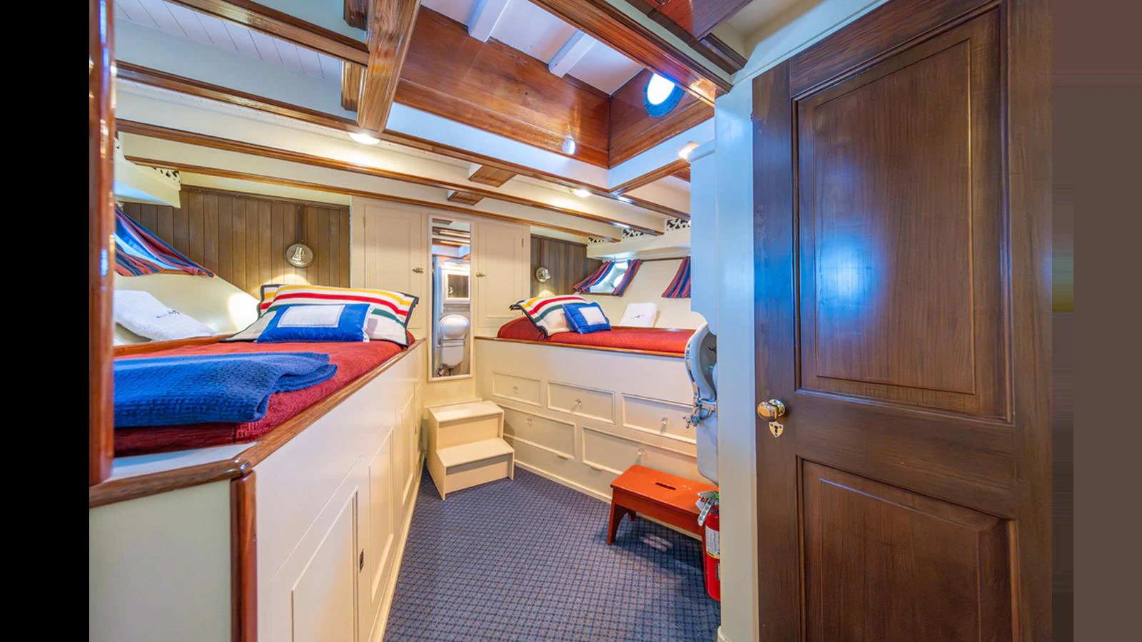 The guest cabin features twin beds with colorful bedding and a warm wooden finish. aboard BLUE PETER Yacht for Sale