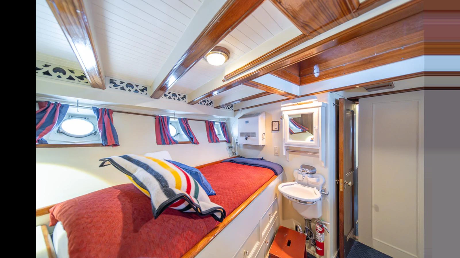 This cozy stateroom features a comfortable bed with vibrant bedding and a compact ensuite bathroom. aboard BLUE PETER Yacht for Sale