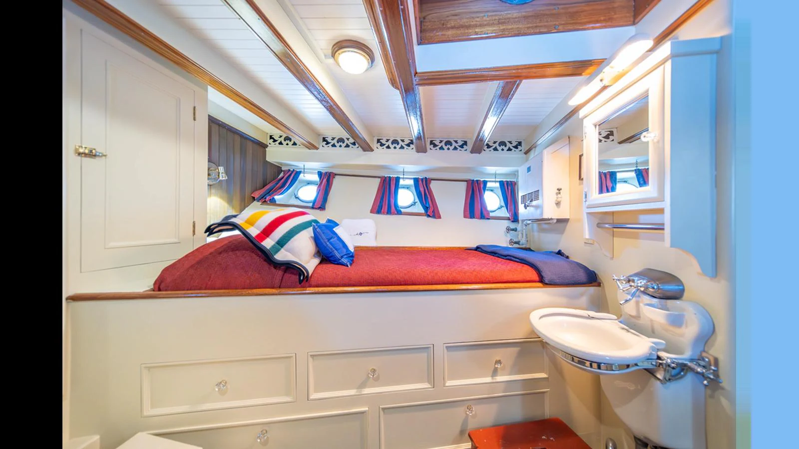 A cozy stateroom featuring a raised bed with ample storage and a compact sink area. aboard BLUE PETER Yacht for Sale