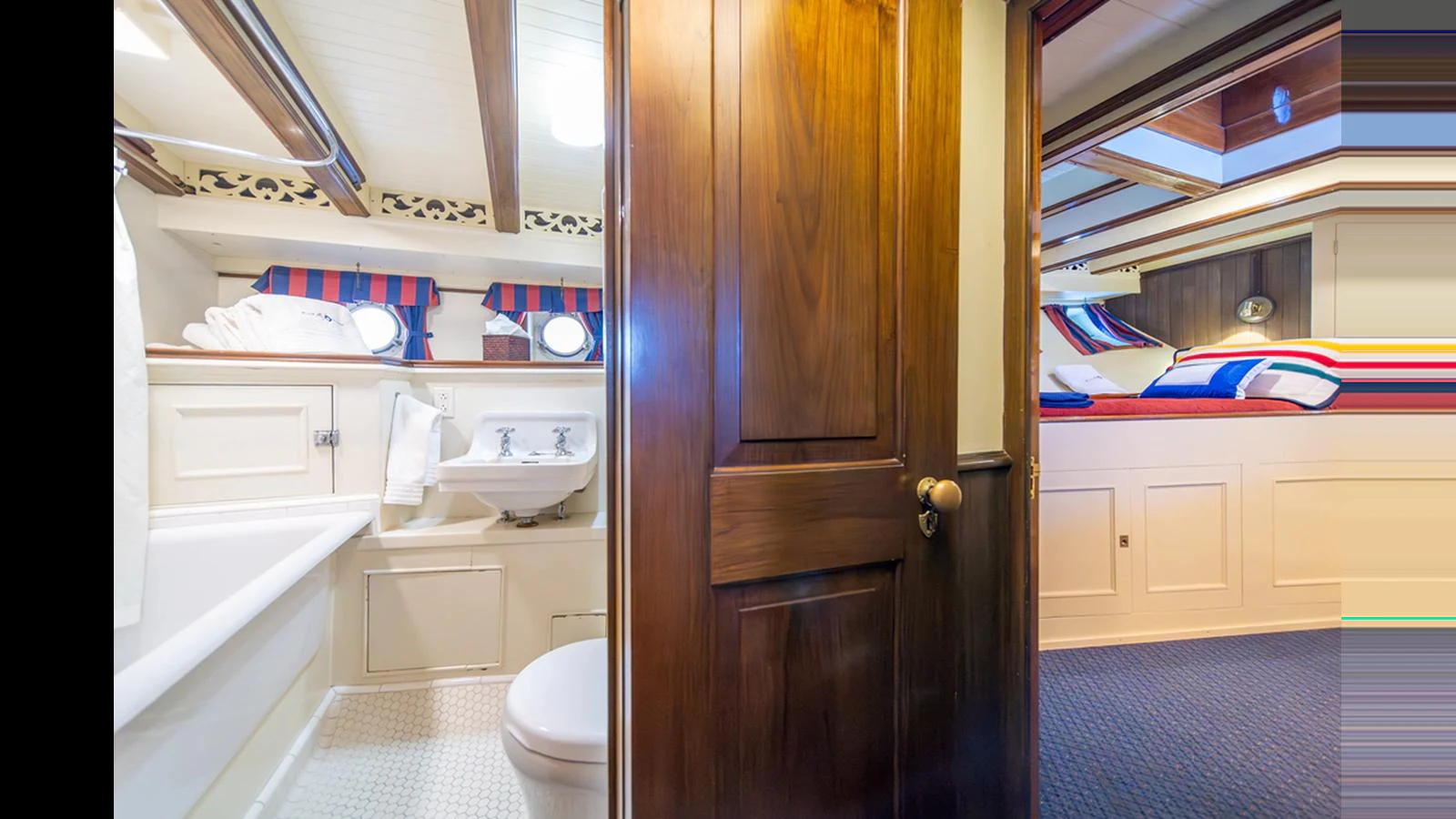 A cozy yacht bathroom with a wooden door, white fixtures, and nautical-themed decor. aboard BLUE PETER Yacht for Sale