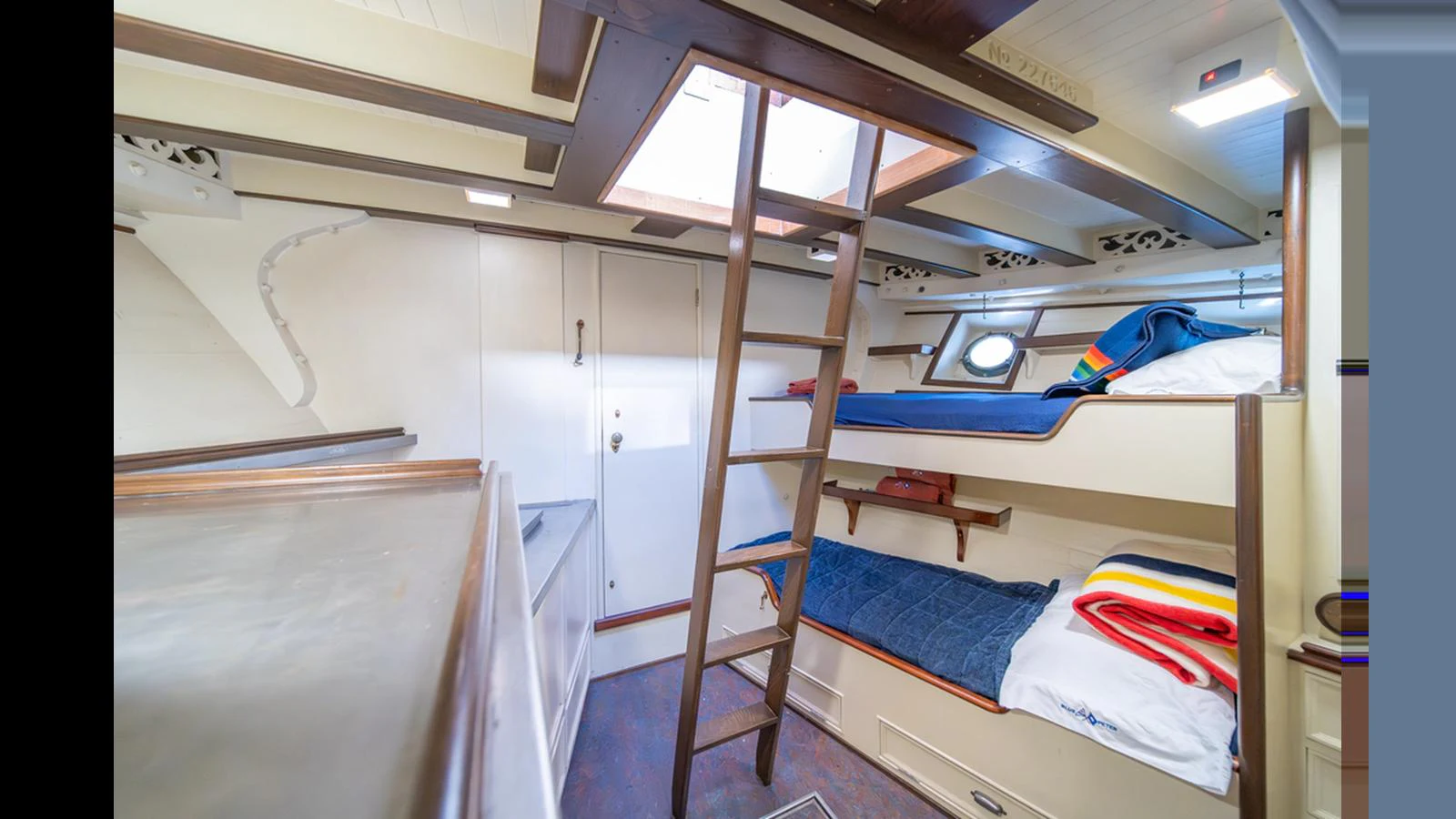 The cozy cabin features bunk beds and a ladder leading to a skylight, creating a warm and inviting atmosphere. aboard BLUE PETER Yacht for Sale