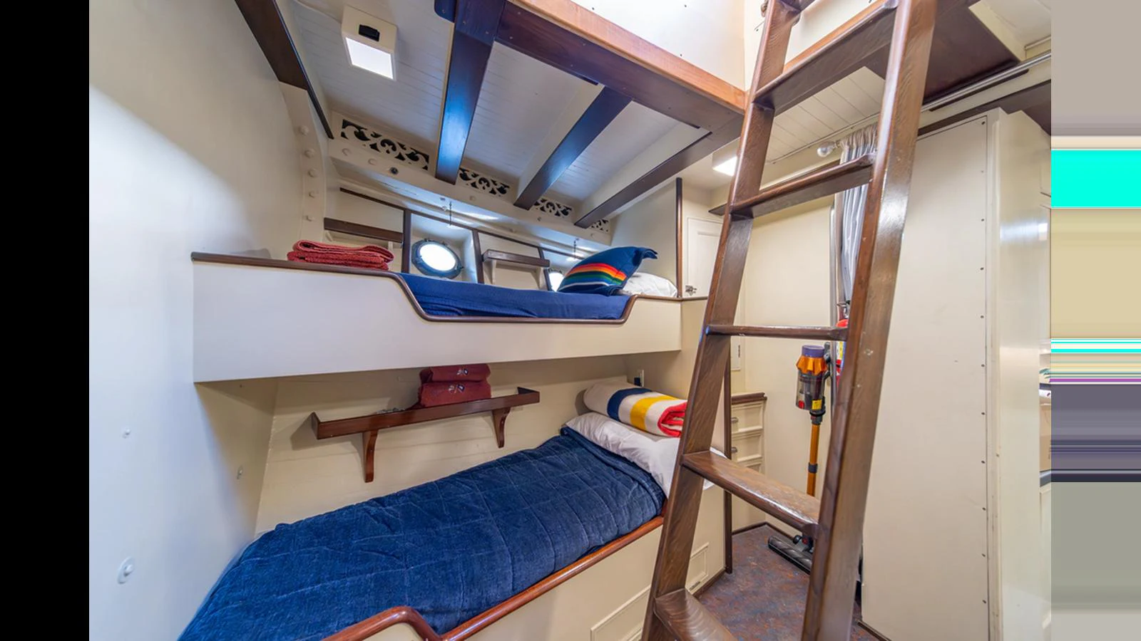 The cozy bunk room features neatly arranged beds and a wooden ladder for easy access. aboard BLUE PETER Yacht for Sale