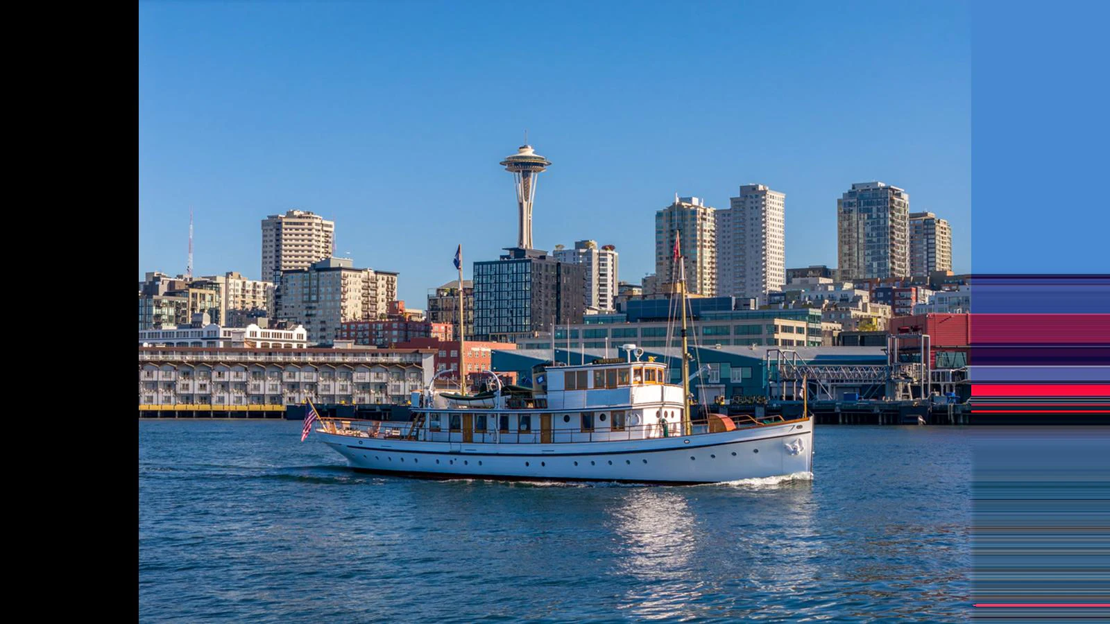 A classic yacht cruises gracefully against a vibrant city skyline. aboard BLUE PETER Yacht for Sale
