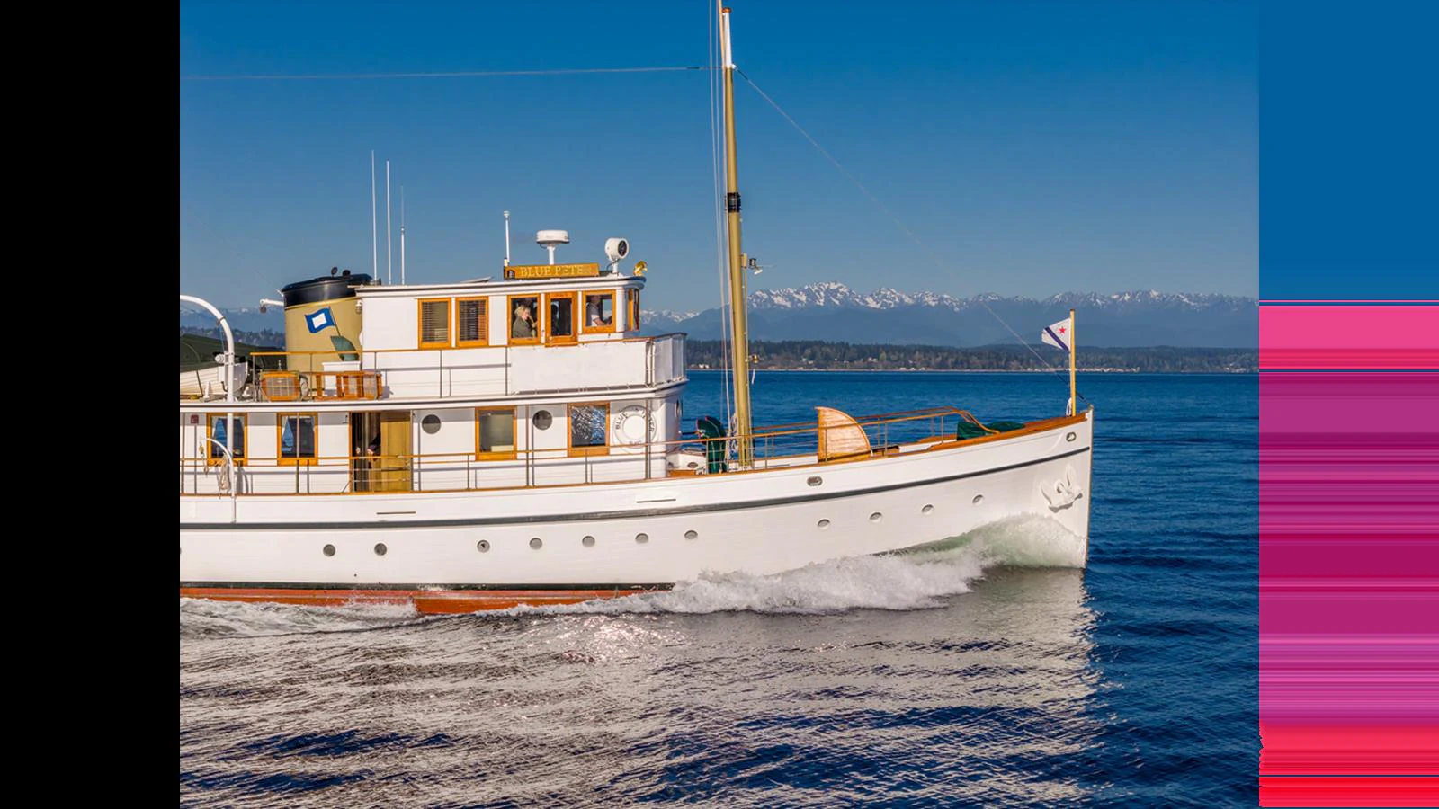 A classic yacht cruises gracefully on calm waters with a stunning mountainous backdrop. aboard BLUE PETER Yacht for Sale