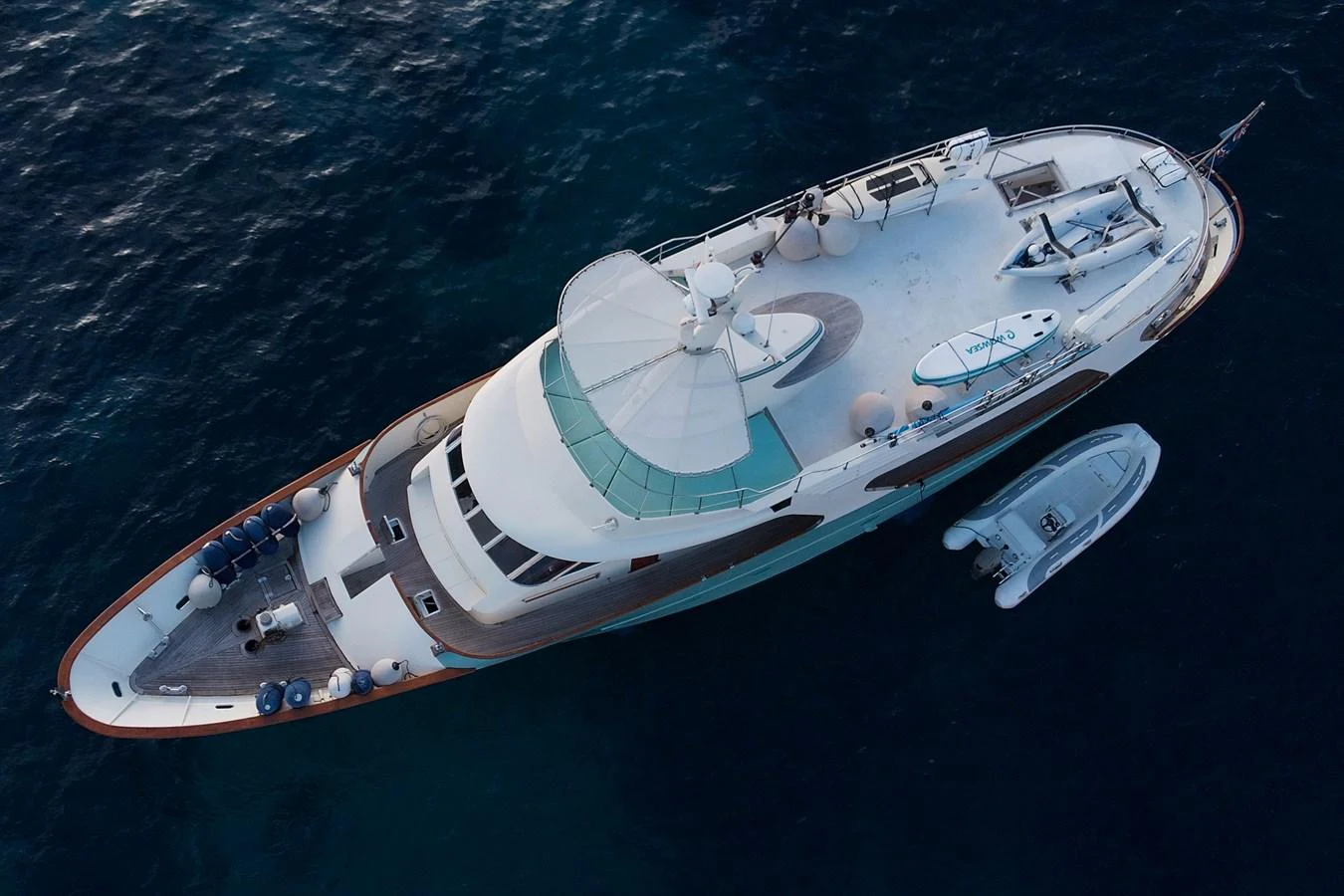 Aerial view of a luxurious yacht cruising on the open sea with a tender alongside. aboard KALANI Yacht for Sale