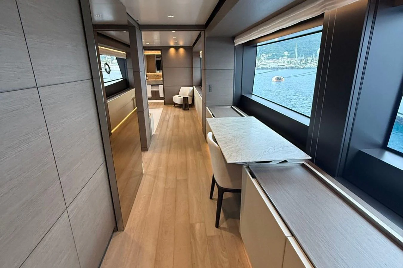 The yacht's salon features elegant wood flooring, large windows, and modern furnishings, offering a luxurious and comfortable space with a view of the sea. aboard ALBUS Yacht for Sale