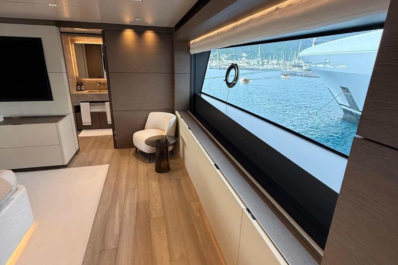 A luxurious interior space with a large window offering a scenic view of the water and nearby yachts. aboard ALBUS Yacht for Sale
