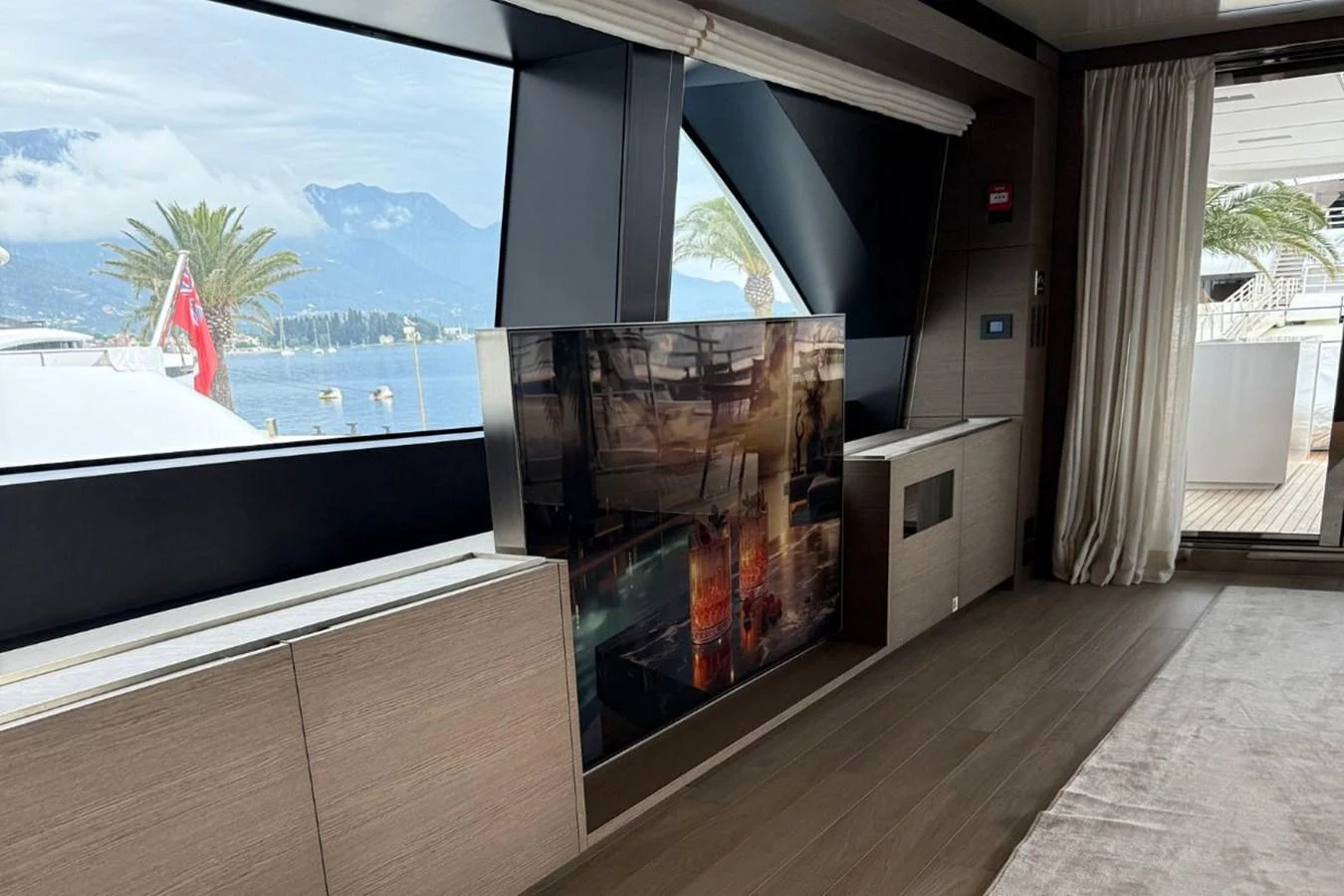 A luxurious interior space with large windows offering a scenic view of the water and mountains. aboard ALBUS Yacht for Sale