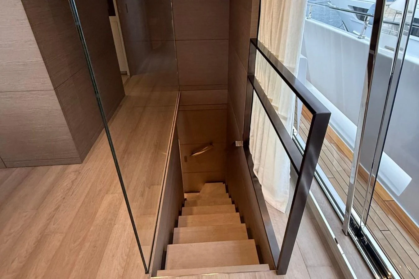 A sleek and modern staircase leads to the lower deck, featuring glass and wood elements. aboard ALBUS Yacht for Sale