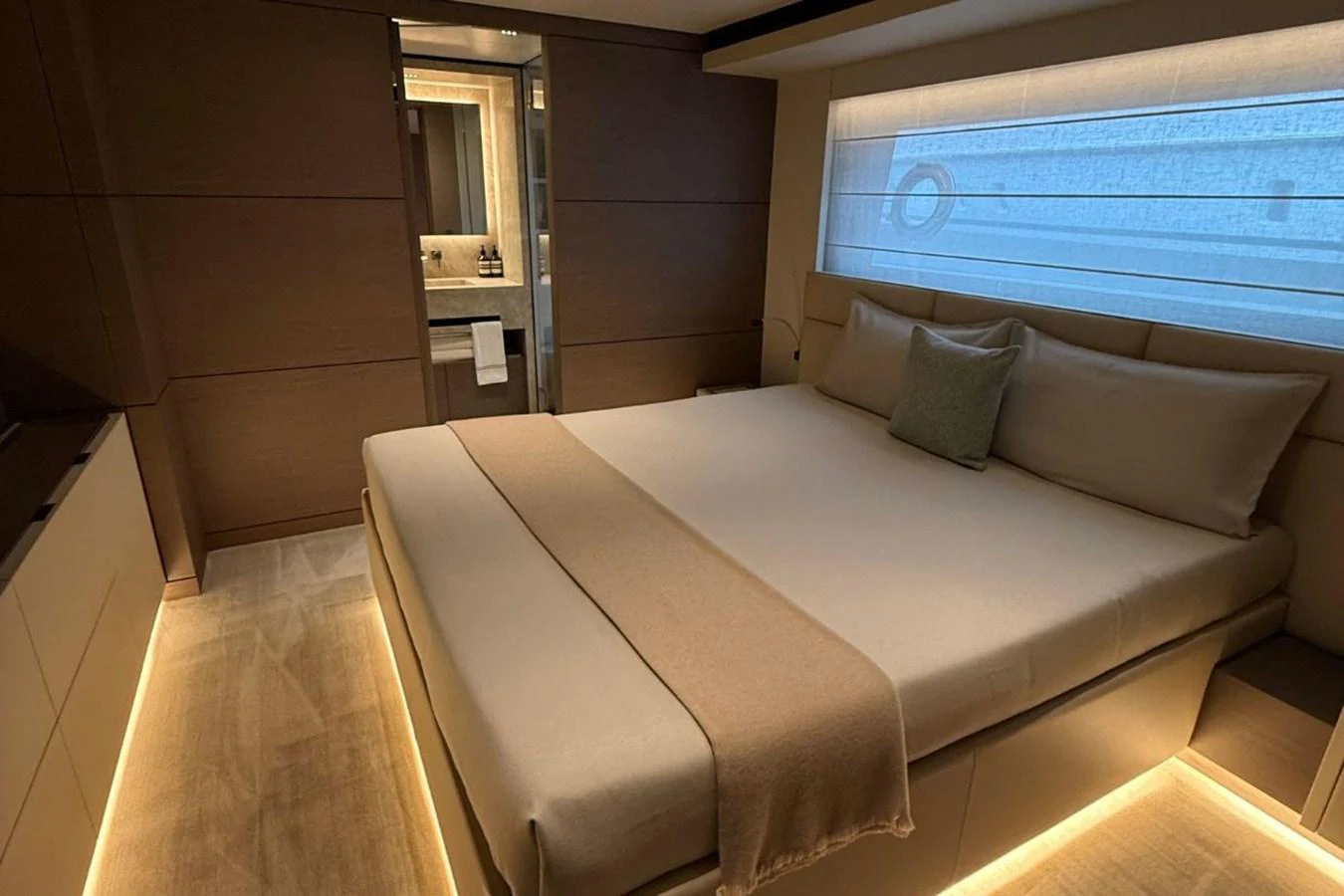 A luxurious stateroom featuring a large bed with ambient lighting and a view into the ensuite bathroom. aboard ALBUS Yacht for Sale