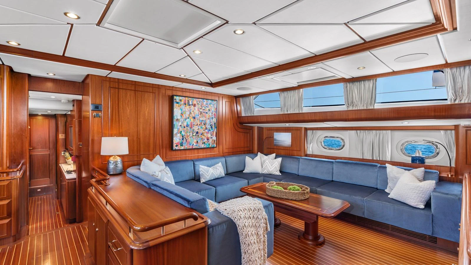 The yacht's salon features a spacious seating area with plush blue sofas and elegant wooden finishes. aboard ISLANDIA Yacht for Sale