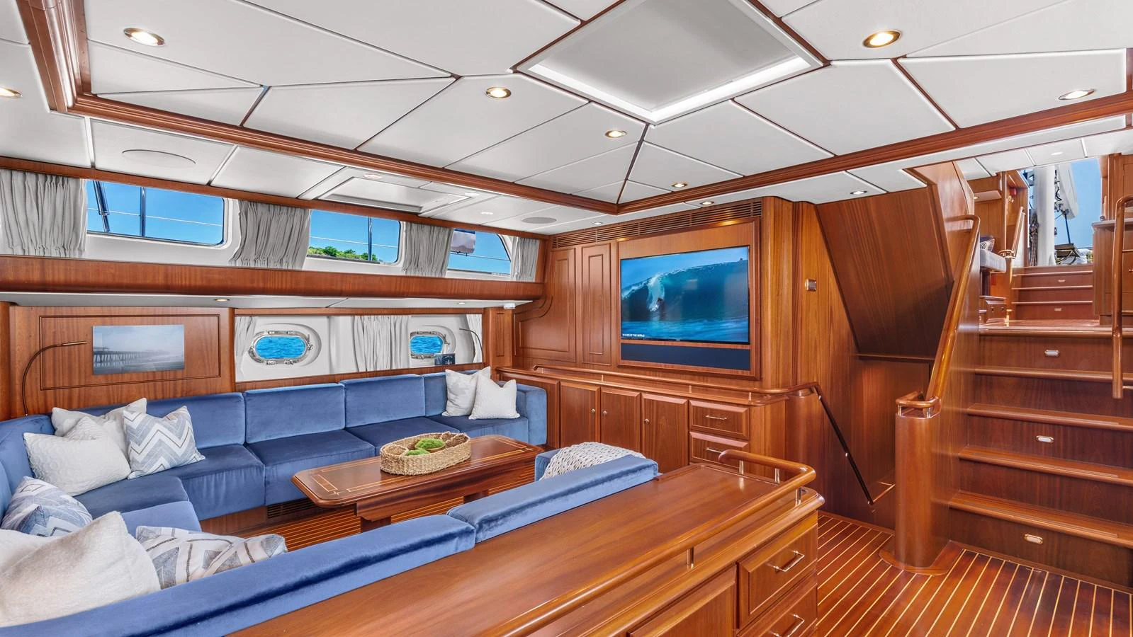 The salon features a spacious seating area with plush blue cushions and a large flat-screen TV, creating a comfortable and inviting atmosphere. aboard ISLANDIA Yacht for Sale