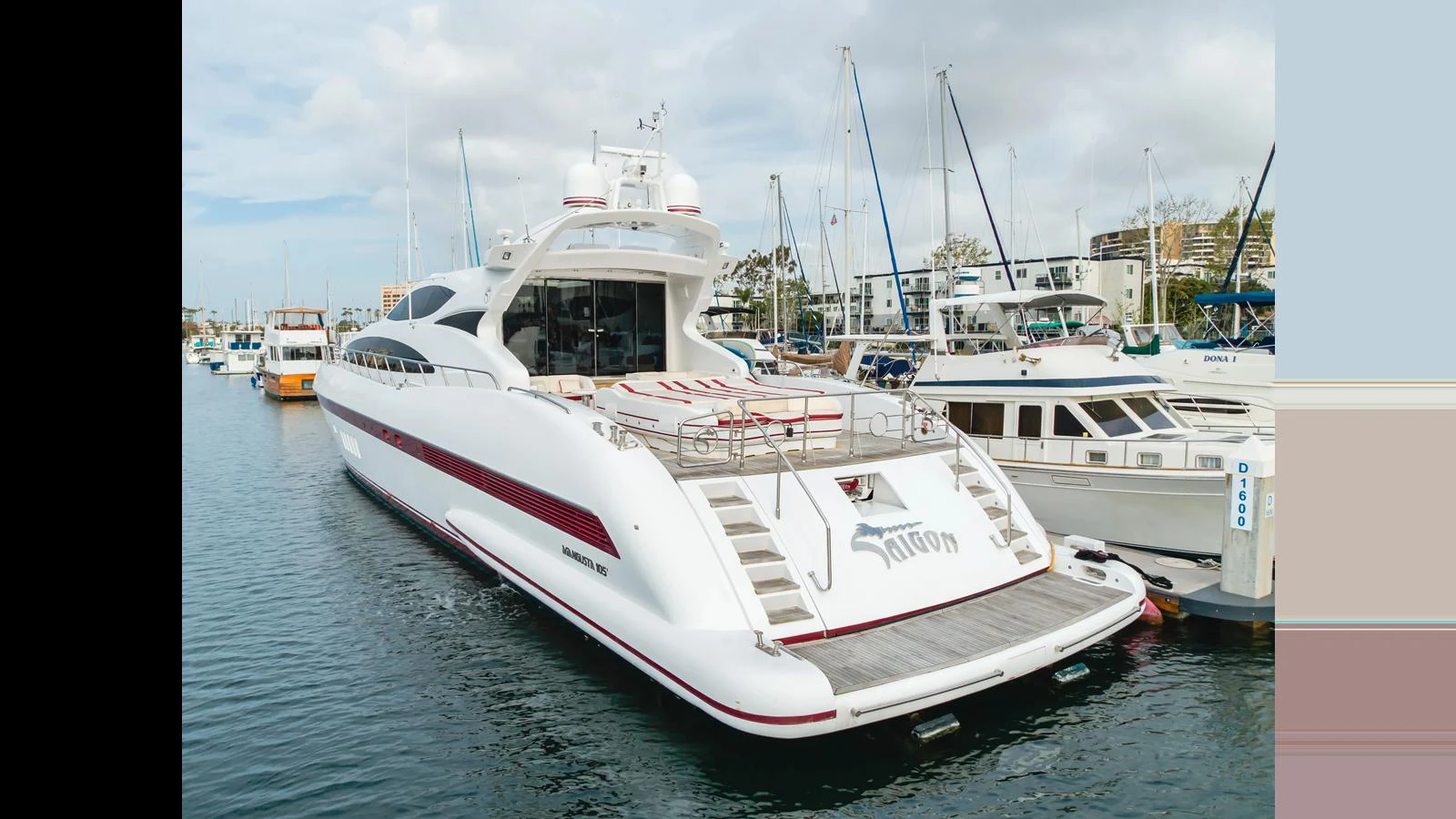 A sleek and modern yacht is docked at a marina, showcasing its spacious aft deck and elegant design. aboard SAIGON Yacht for Sale