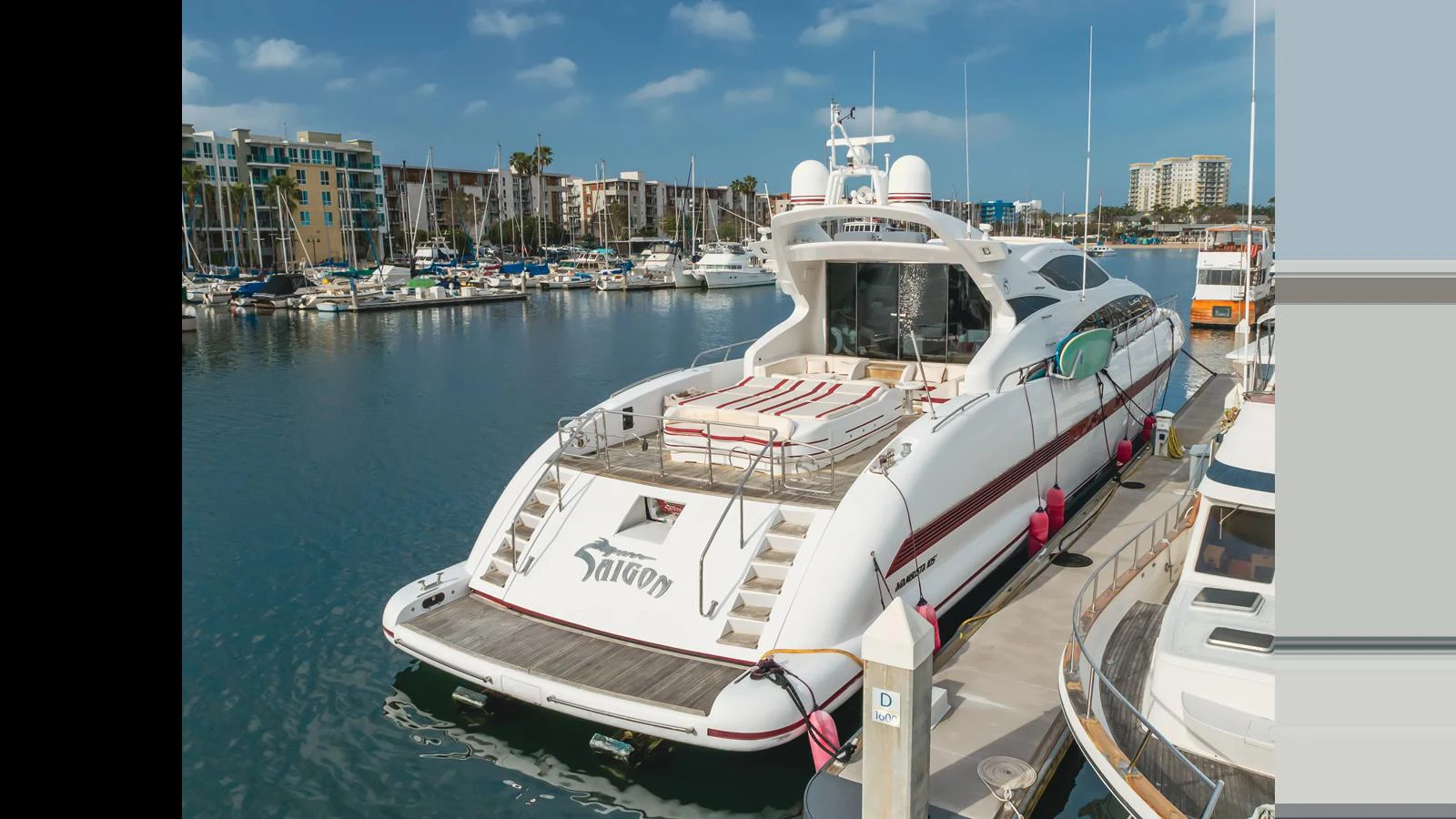 The yacht is docked in a marina, showcasing its sleek aft deck and luxurious design. aboard SAIGON Yacht for Sale