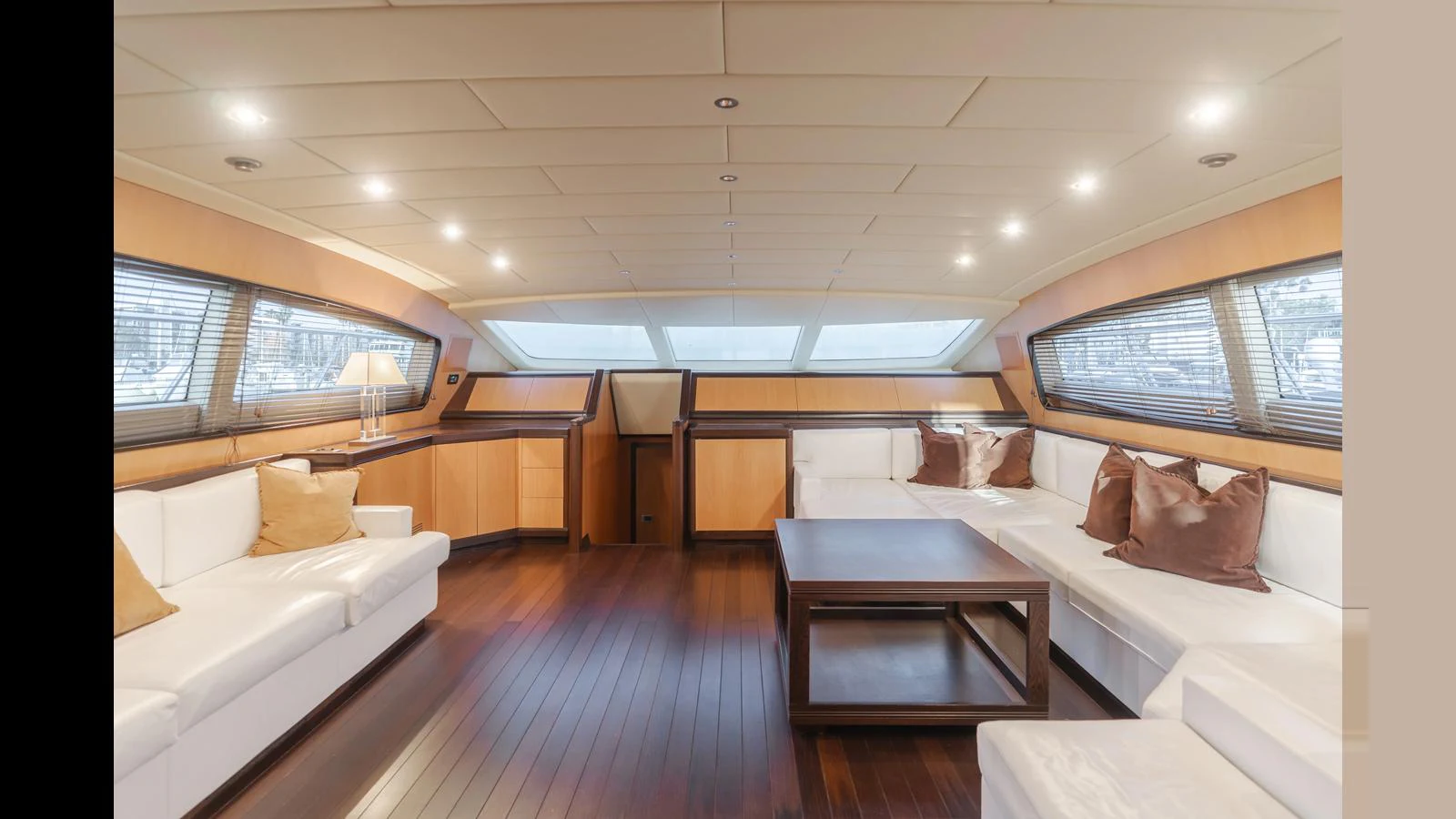 The spacious salon features elegant wood flooring, plush white seating, and ample natural light through large windows. aboard SAIGON Yacht for Sale
