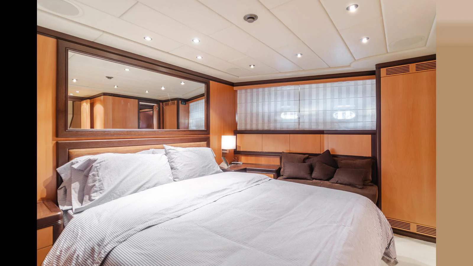 The stateroom features a luxurious bed with elegant wood paneling and soft lighting. aboard SAIGON Yacht for Sale