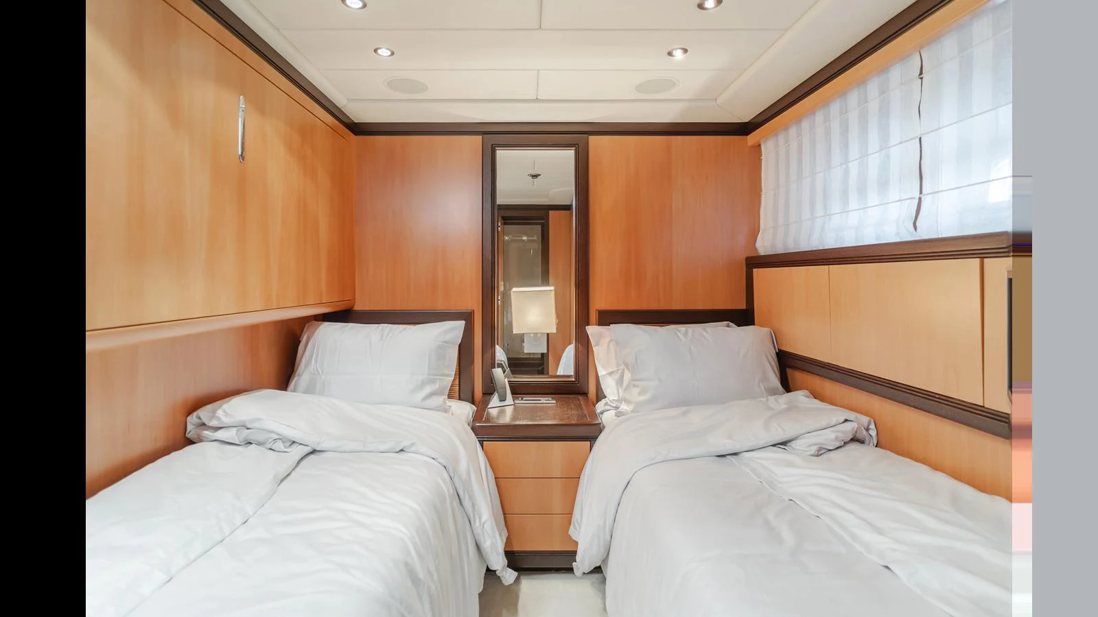 A cozy twin stateroom with wooden paneling and soft lighting. aboard SAIGON Yacht for Sale