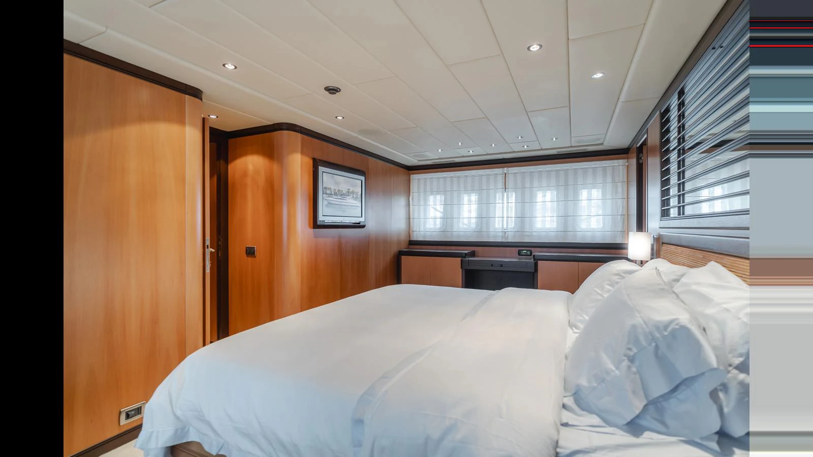 The stateroom features a comfortable bed with elegant wood paneling and ample natural light. aboard SAIGON Yacht for Sale
