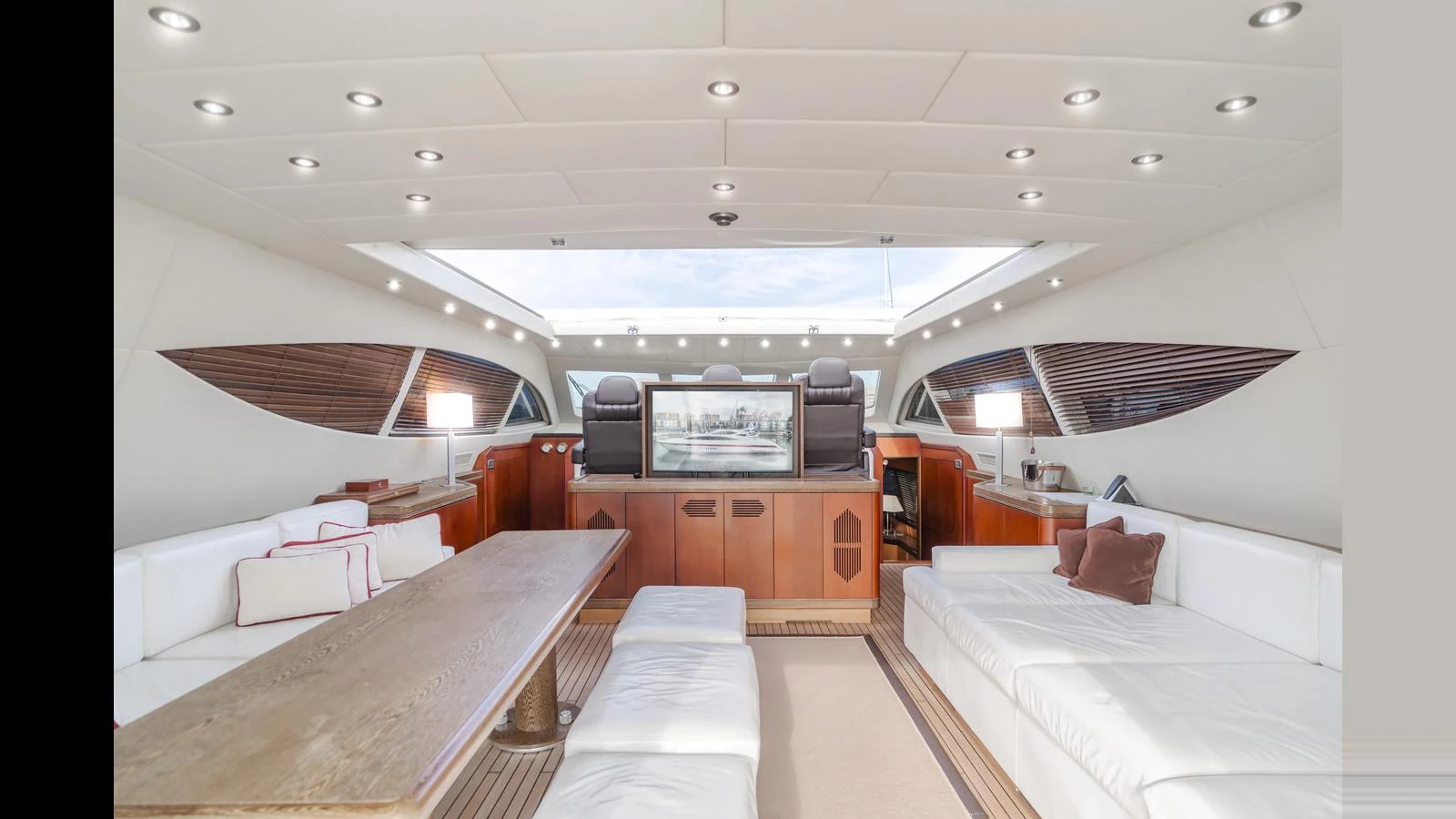 The spacious salon features plush white seating, a wooden dining table, and ample natural light from the large windows and skylight. aboard SAIGON Yacht for Sale