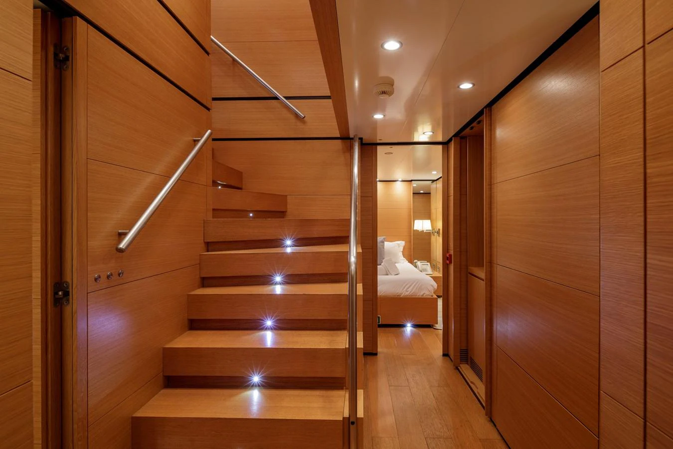 The yacht's interior features a sleek wooden staircase leading to a cozy stateroom. aboard BOLARO Yacht for Sale