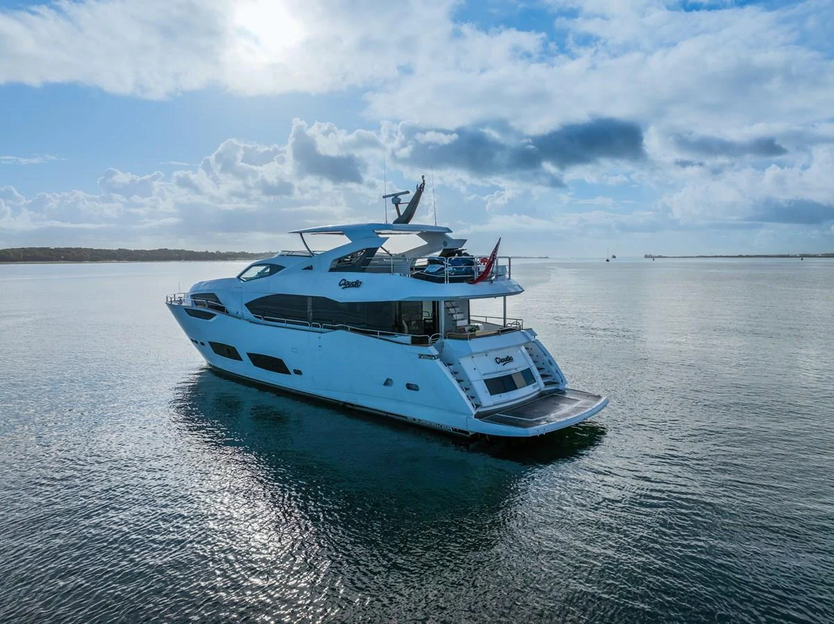 A luxurious yacht glides gracefully on calm waters under a partly cloudy sky. aboard CLOUDIA Yacht for Sale