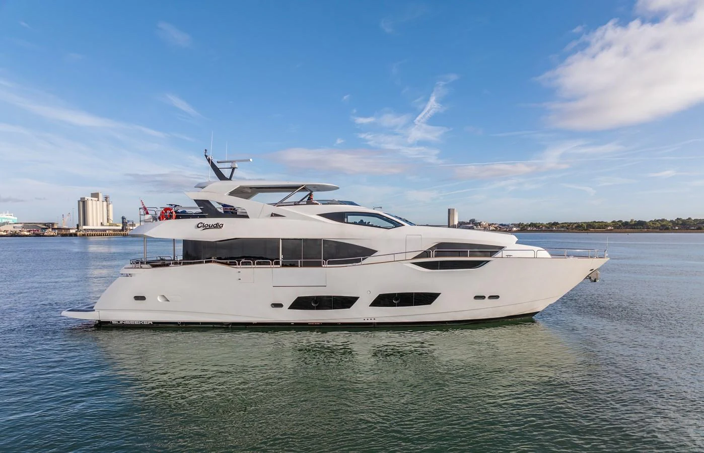 A sleek and modern yacht cruising on calm waters under a clear blue sky. aboard CLOUDIA Yacht for Sale