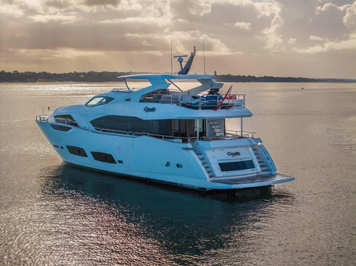A sleek and modern yacht glides gracefully on calm waters under a cloudy sky. aboard CLOUDIA Yacht for Sale